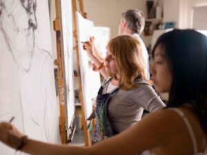 Artists sketching on canvases in a studio.