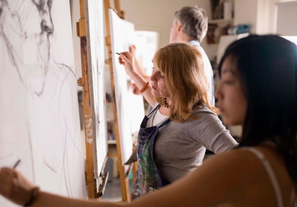 Artists sketching on canvases in a studio.
